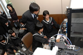 Junior high school students enjoying hands-on experience of the cell manipulation system