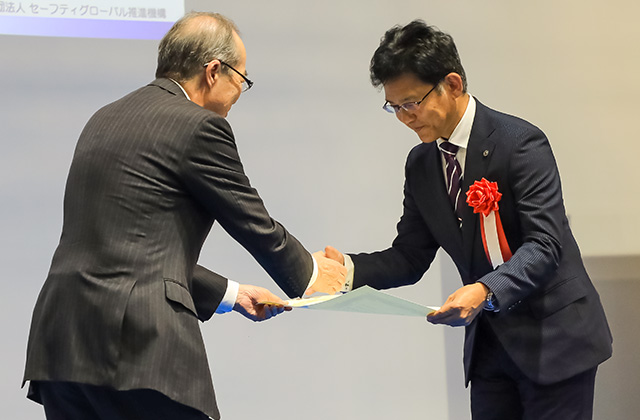 
NSK Group Manager Kenichiro Hara, Environment, Health & Safety Office receives the Mukaidono Safety Award on behalf of NSK.
