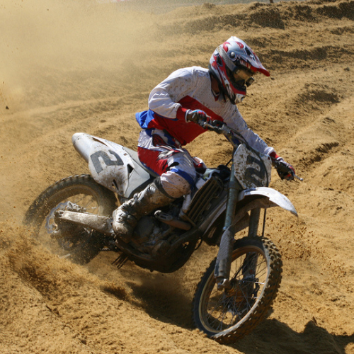 Picture of person on dirtbike on dirt track, creating a dust cloud.