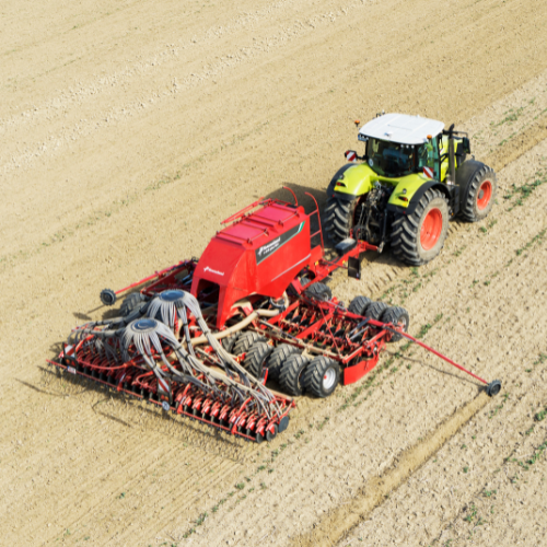 Picture of tractor dragging combine harvester over field.