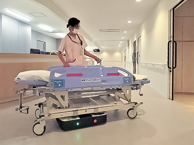 
同ロボットを取り付けたストレッチャー(湘南鎌倉総合病院で撮影。写真では看護補助者が左手でリモコン操作し、ストレッチャーを移動中)
